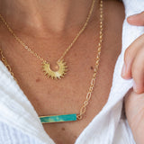 Gold necklace with a green pendant worn by a person