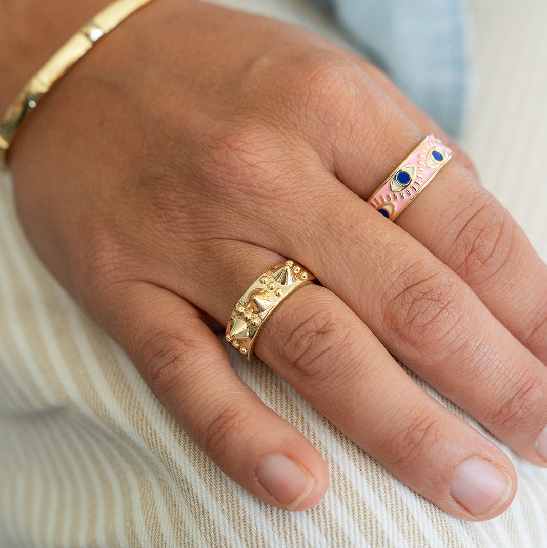 Hand wearing two gold rings with a blurred background