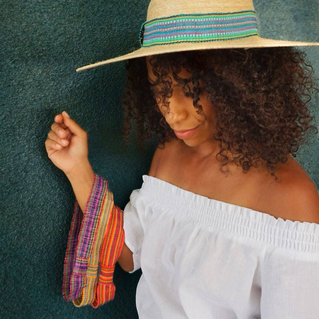 Woman wearing a straw hat with a colorful band against a green background
