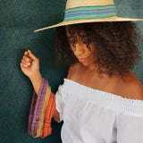 Woman wearing a straw hat with a colorful band against a green background